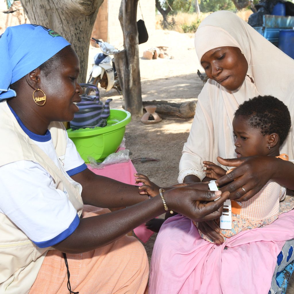 CHW Bounkoungou Alice examines baby Salimata (in the arms of her mother Alimata) in Kiebé, Burkina Faso.