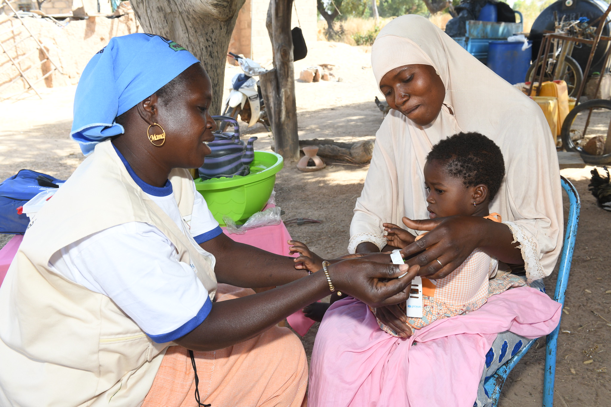CHW Bounkoungou Alice examines baby Salimata (in the arms of her mother Alimata) in Kiebé, Burkina Faso.